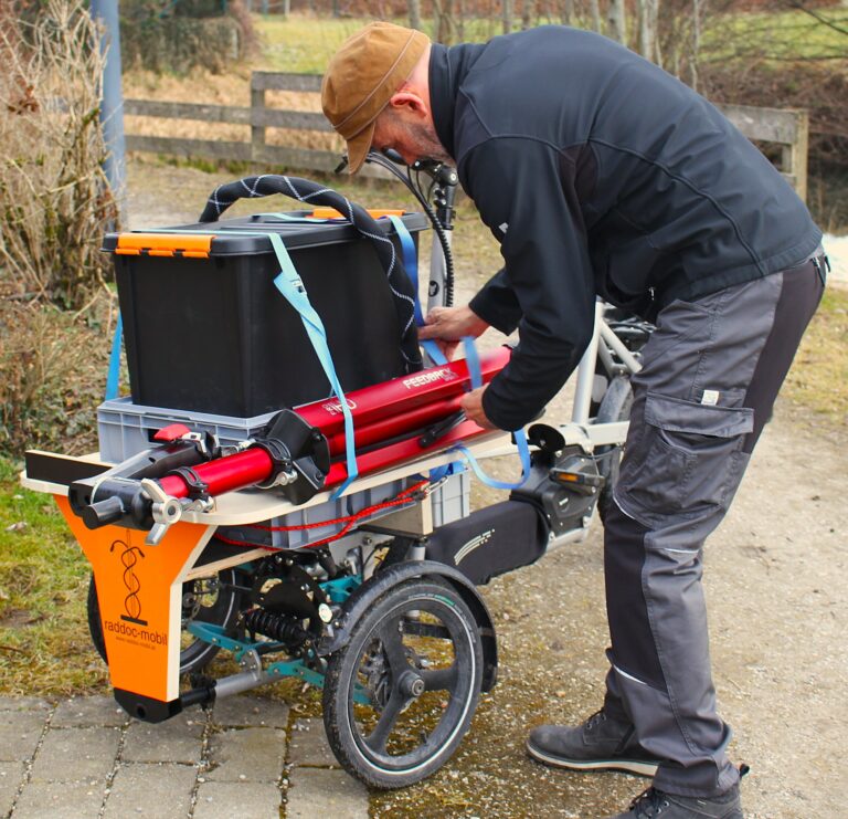 Raddoc holt etwas aus seinem Lastenrad